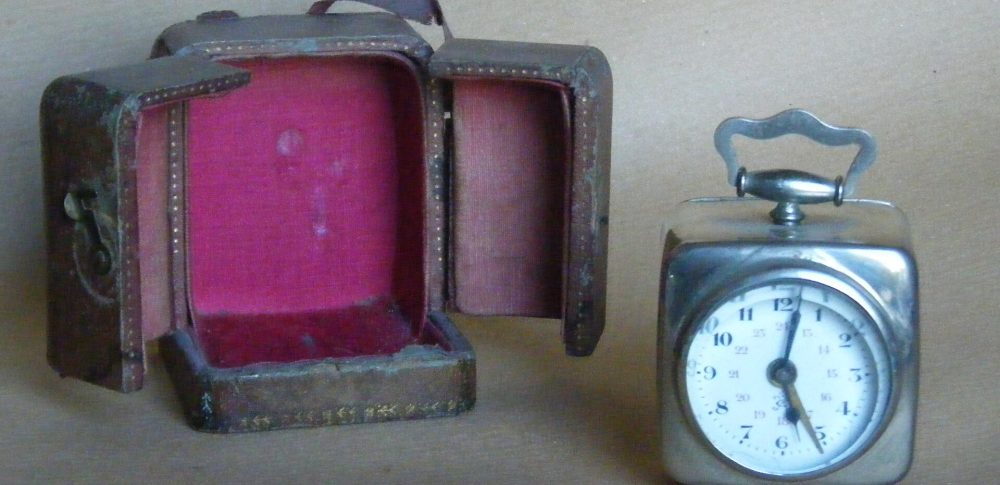 Despertador antiguo de viaje junto a su estuche de piel