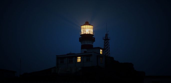 Faro encendido de noche sobre un acantilado oscuro